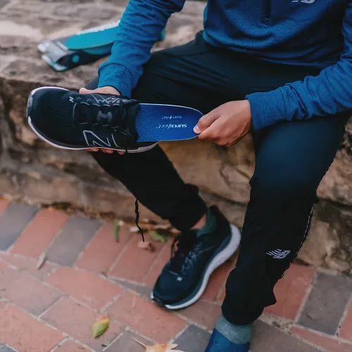 A runner slides a Superfeet insole into their shoe.