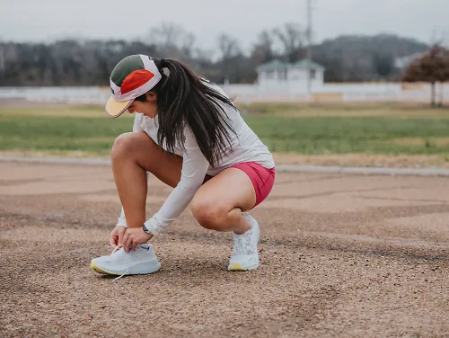 A woman laces up her running shoes. 